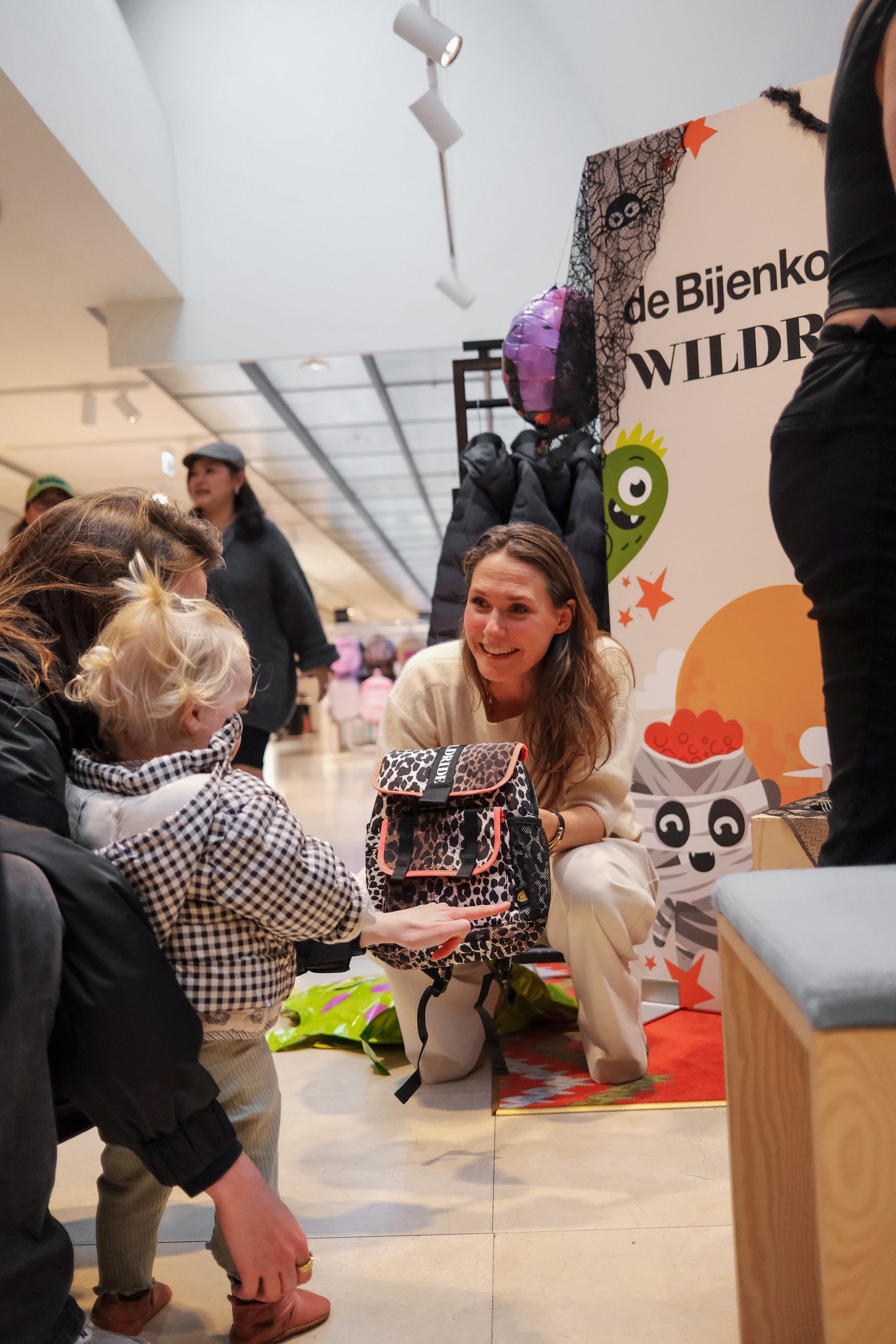 Toddler interacting with Wildride team at Halloween event inside De Bijenkorf store