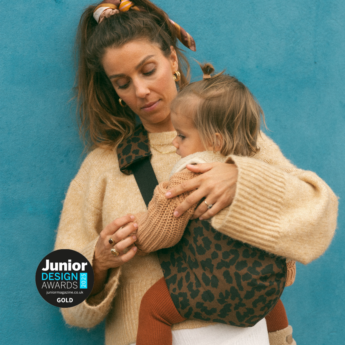 Parent carrying child in Wildride toddler carrier, Junior Design Awards Gold 2025 badge