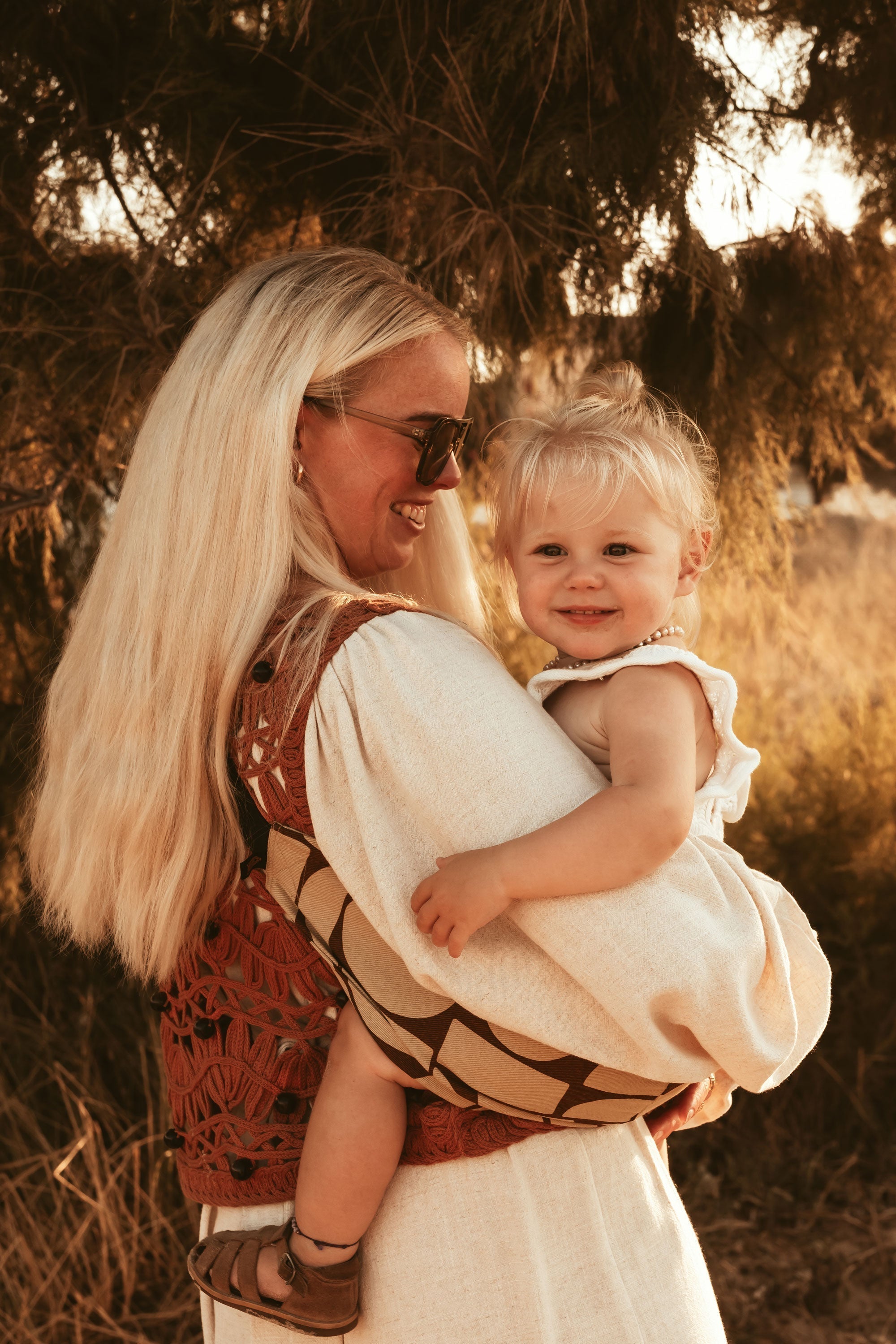 Parent carrying toddler in Wildride toddler carrier outdoors