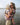 Mother carrying her child in a Wildride Toddler Carrier Vintage Rose, a lightweight ergonomic hip carrier, standing on the beach at low tide.